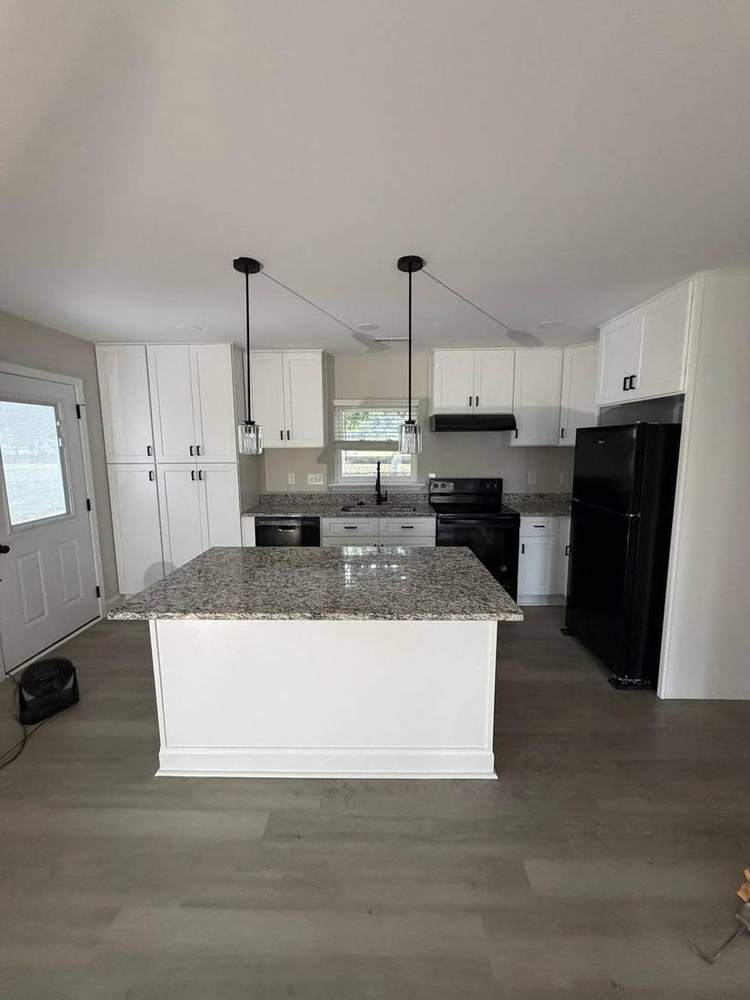 Finished kitchen with white shaker cabinets, granite island and pendant lights